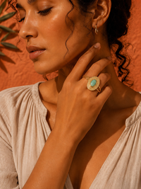 Femme portant la Bague PALMÉA amazonite et or 24k sur fond terracotta — Univers Aquatique, La Parisienne des Îles